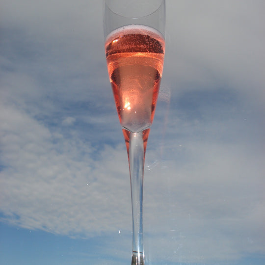 Goat bubbles rose in a glass with clouds in the background