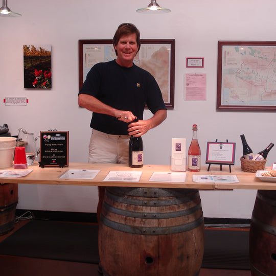 Norm Yost in the tasting room. Old table with barrels being used
